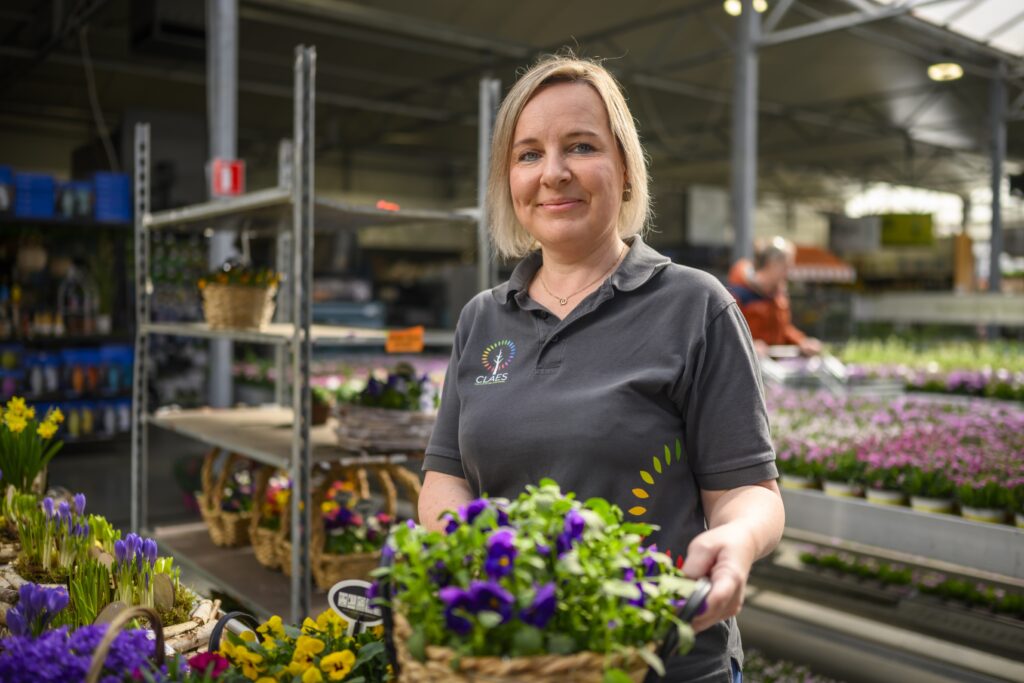 Een blije medewerker van Tuincenter Claes aan het werk.